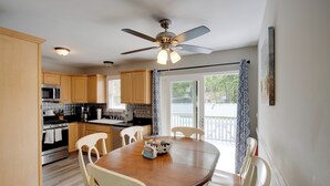 A kitchen with wooden cabinets, a microwave, an oven, and a dining table with chairs. - Charming Somers Point House w/ Private Pool! (Somers Point)