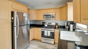 A kitchen with wooden cabinets, stainless steel appliances, a microwave, stove, and a coffee maker. - Charming Somers Point House w/ Private Pool! (Somers Point)