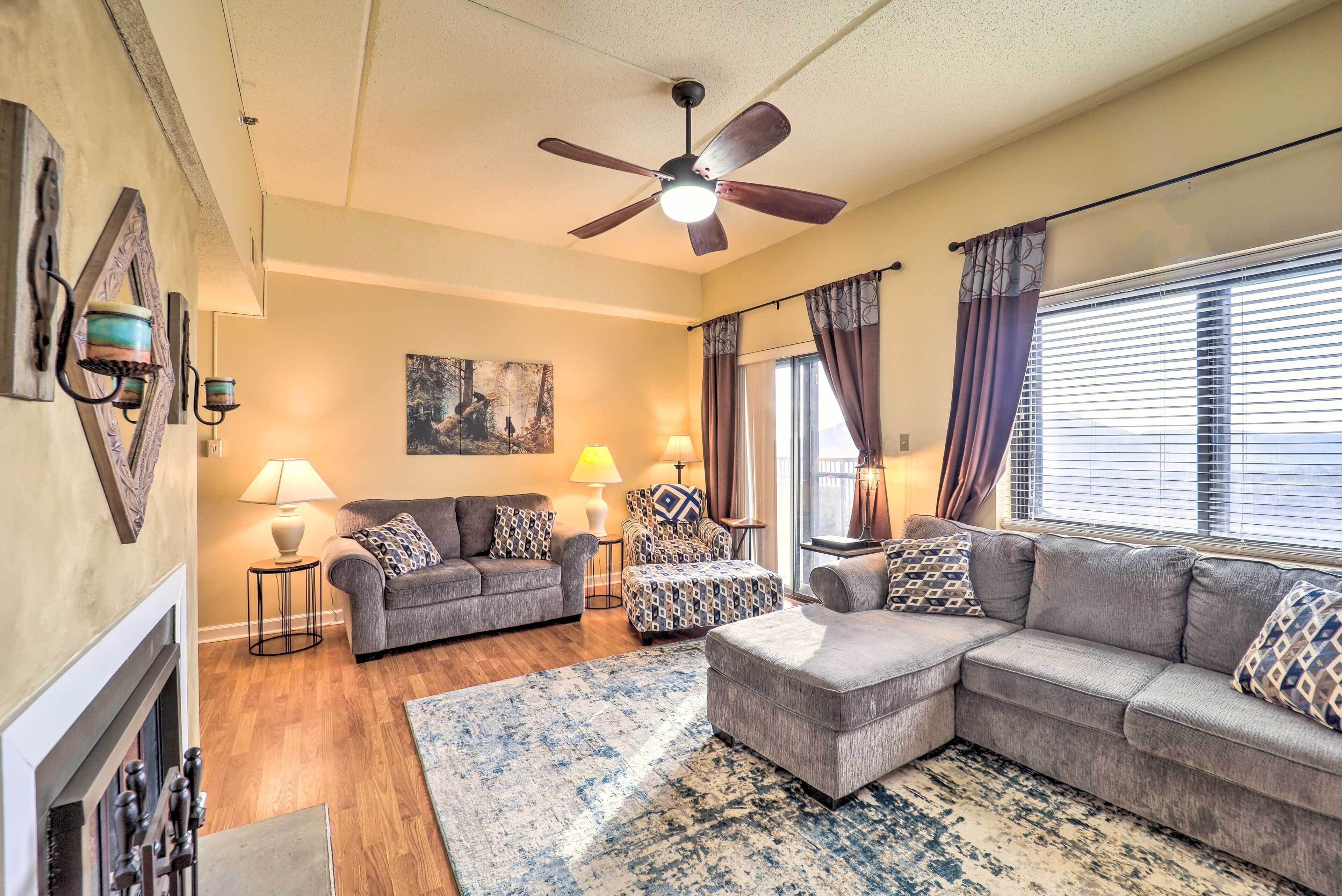 A living room with a fireplace, two sofas, a coffee table, and a ceiling fan.