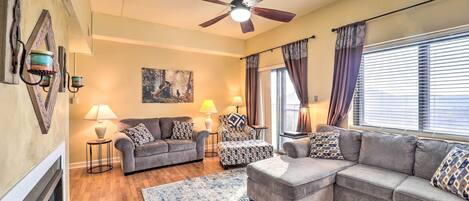 A living room with a fireplace, two sofas, a coffee table, and a ceiling fan.