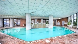En inomhuspool med klart vatten, omgiven av kakelbeklädd golv och ett tak med ett rutmönster.
