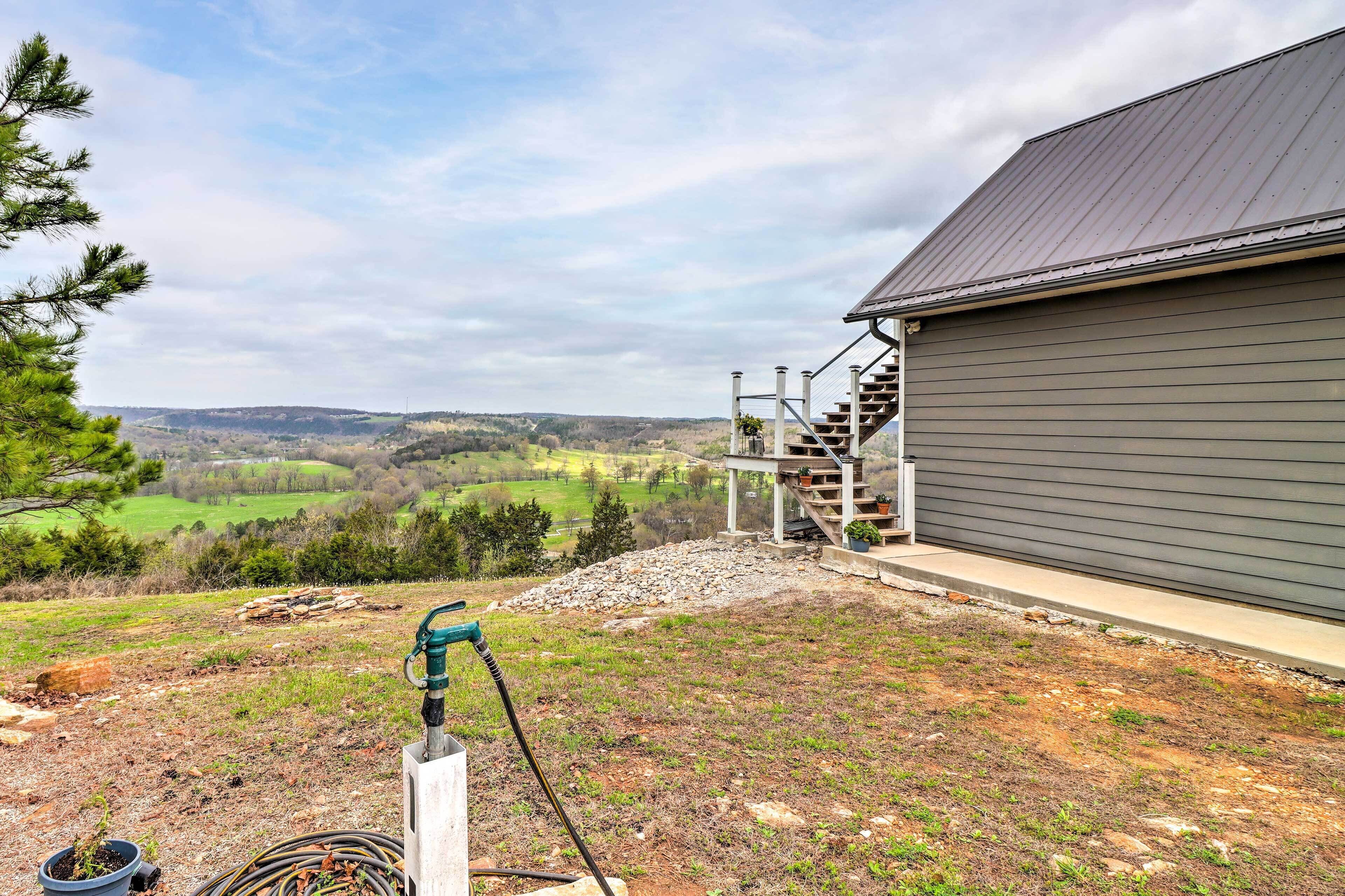 A house with a metal roof, a staircase leading to a deck, and a view of a green valley.