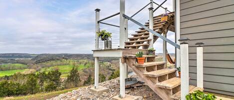 A wooden outdoor staircase leading to a deck with a view of a valley.