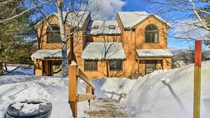 Une cabane en bois, dont le toit est recouvert de neige, et un escalier en bois qui mène à l’entrée.