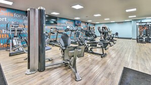 A gym with various exercise machines, a wooden floor, and motivational wall art. - Cozy Pigeon Condo, Near Lake Huron Beaches! (Pigeon)