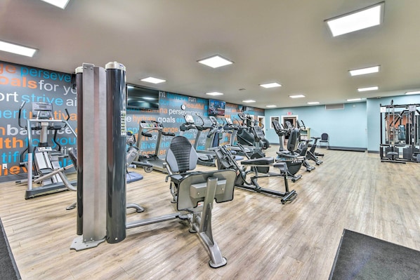 A gym with various exercise machines, a wooden floor, and motivational wall art. - Cozy Pigeon Condo, Near Lake Huron Beaches! (Pigeon)