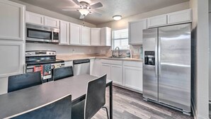 A kitchen with white cabinets, a stainless steel refrigerator, a microwave, an oven, and a ceiling fan. - Bright Brownwood Home With On-site River Access! (Bangs)