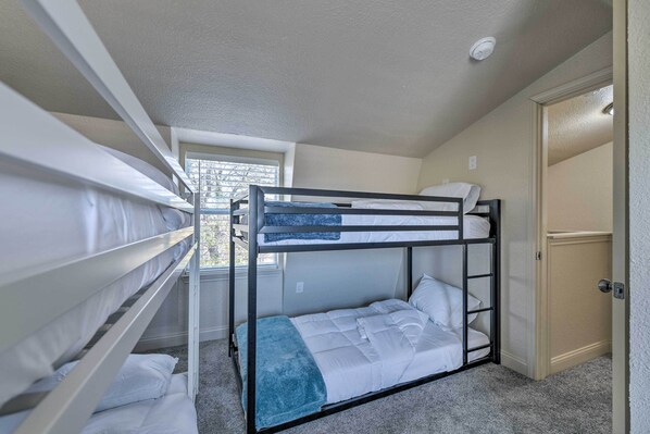 Dormitorio con literas, ventana, puerta y piso alfombrado.