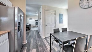 A modern kitchen with a stainless steel refrigerator, a dining area with a table and chairs, and a hallway leading to a living area. - Bright Brownwood Home With On-site River Access! (Bangs)