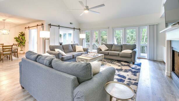 A spacious living room with a large grey sofa, a coffee table, and a fireplace. - Golf, Dine & Swim: Sleek Palmetto Dunes Home! (Hilton Head Island)
