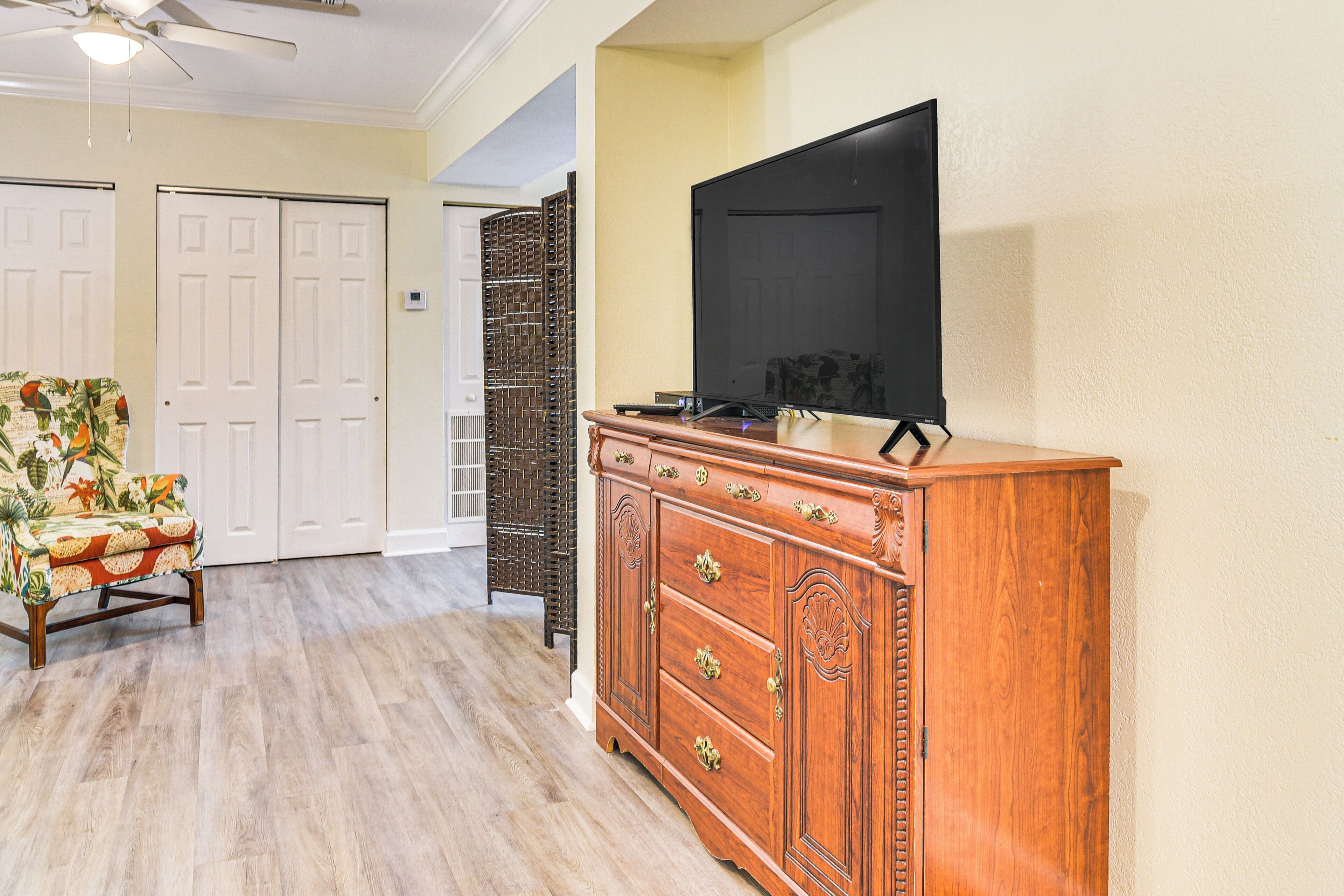 Una habitación con un aparador de madera, un televisor y un banco estampado.