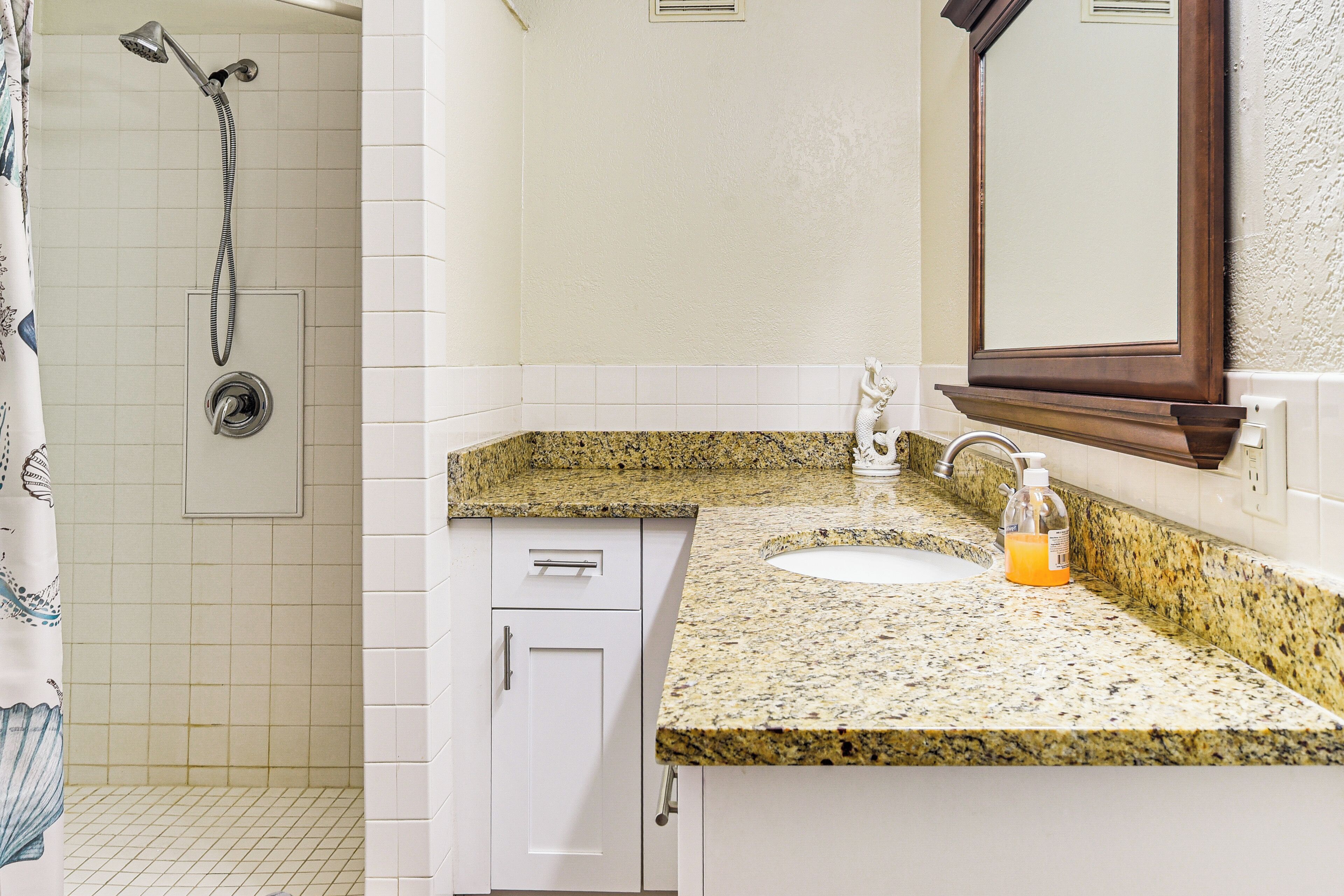 A bathroom with a shower, a sink, and a mirror.