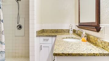 A bathroom with a shower, a sink, and a mirror.