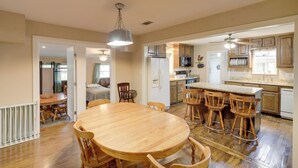 Una cocina amplia con armarios de madera, una isla central con taburetes de bar y un comedor con una mesa redonda grande y sillas.