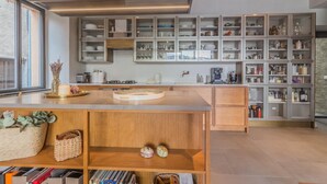 Eine moderne Küche mit Holzausstattung, einer zentralen Kochinsel und verschiedenen Küchengeräten und Utensilien.