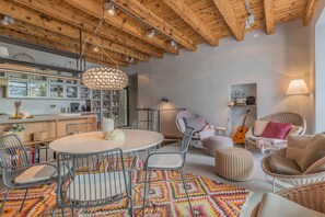 A cozy living room with a round table, chairs, a colorful rug, and a guitar. - Casa Stella in Varenna (Varenna)