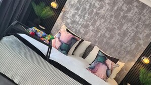 A modern bedroom with a bed, pillows, and a nightstand. - 1 Bed Flat - Sleeps 2 - Jacuzzi - Parking - Wifi (Birmingham)