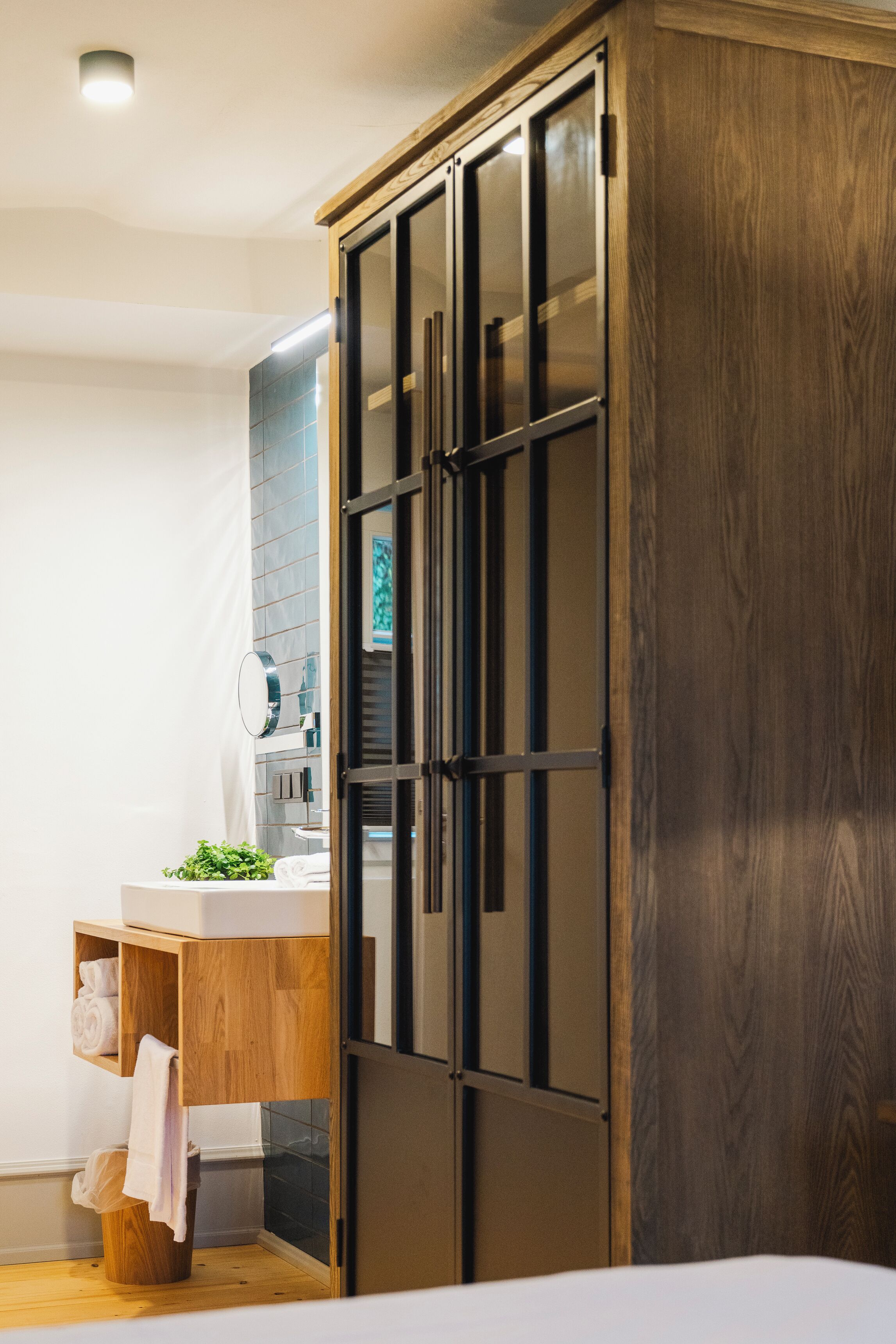A modern bathroom with a wooden vanity, a large mirror, and a wooden wardrobe.