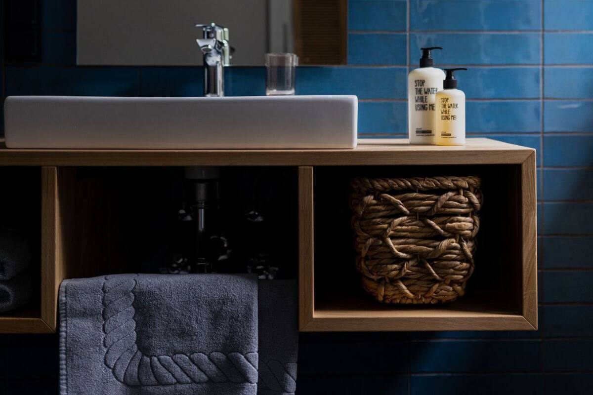 Une salle de bain avec un lavabo, un miroir et des murs recouverts de carreaux bleus.
