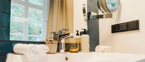 A modern bathroom with a large white sink, a mirror, and a window with curtains.