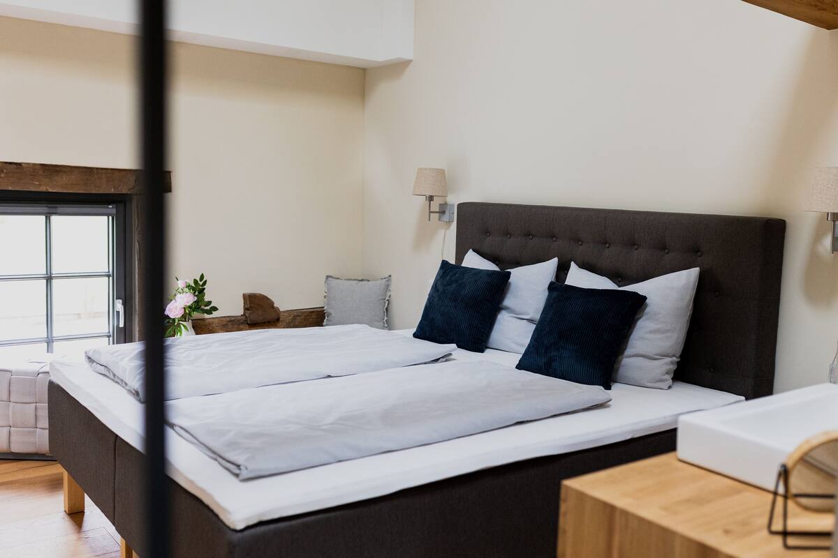 Une chambre à coucher moderne avec un grand lit, une tête de lit en bois et une table de chevet avec une lampe.