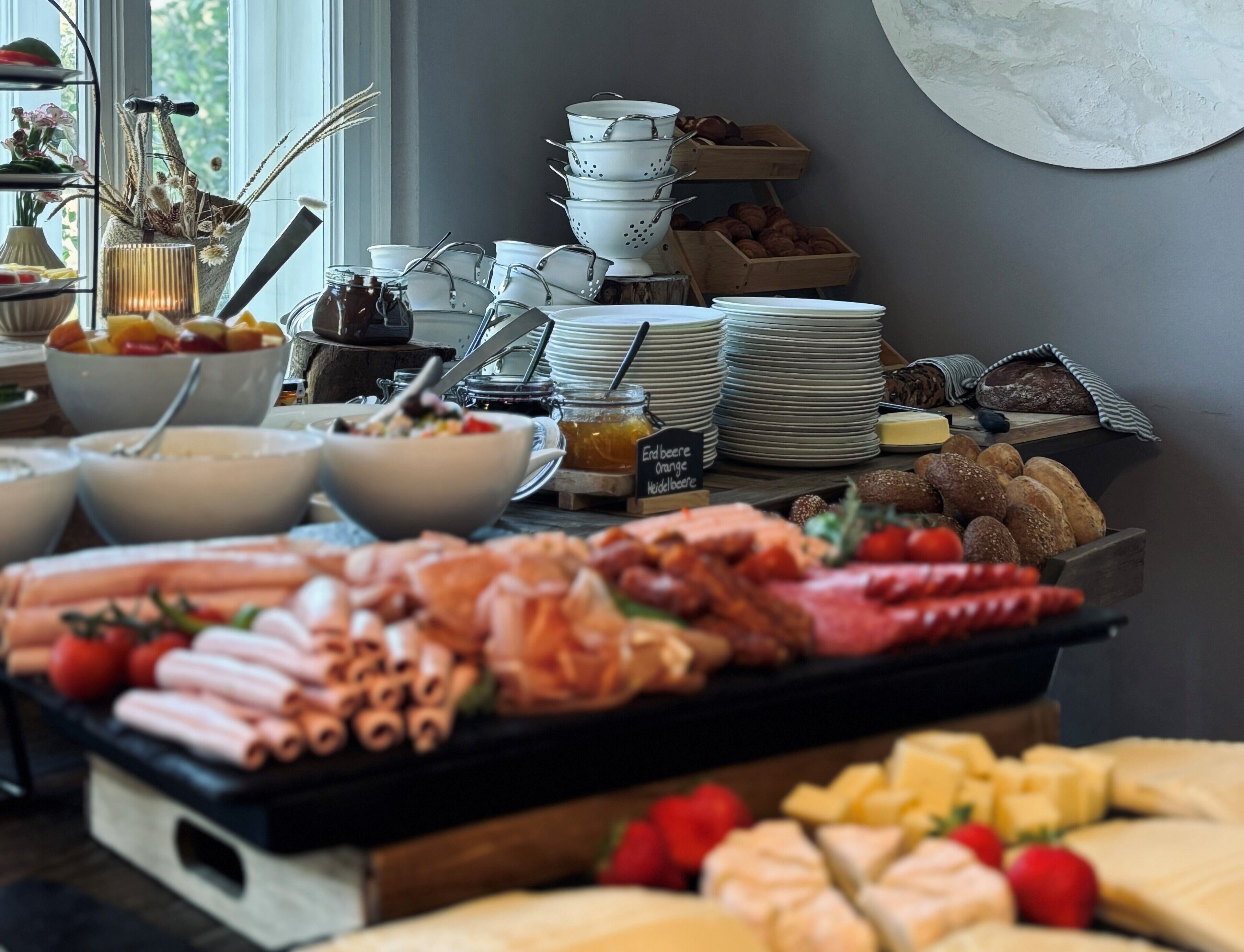 Een buffet met diverse soorten eten, zoals vleeswaren, kazen en fruit.