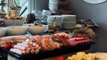 Een buffet met diverse soorten eten, zoals vleeswaren, kazen en fruit.