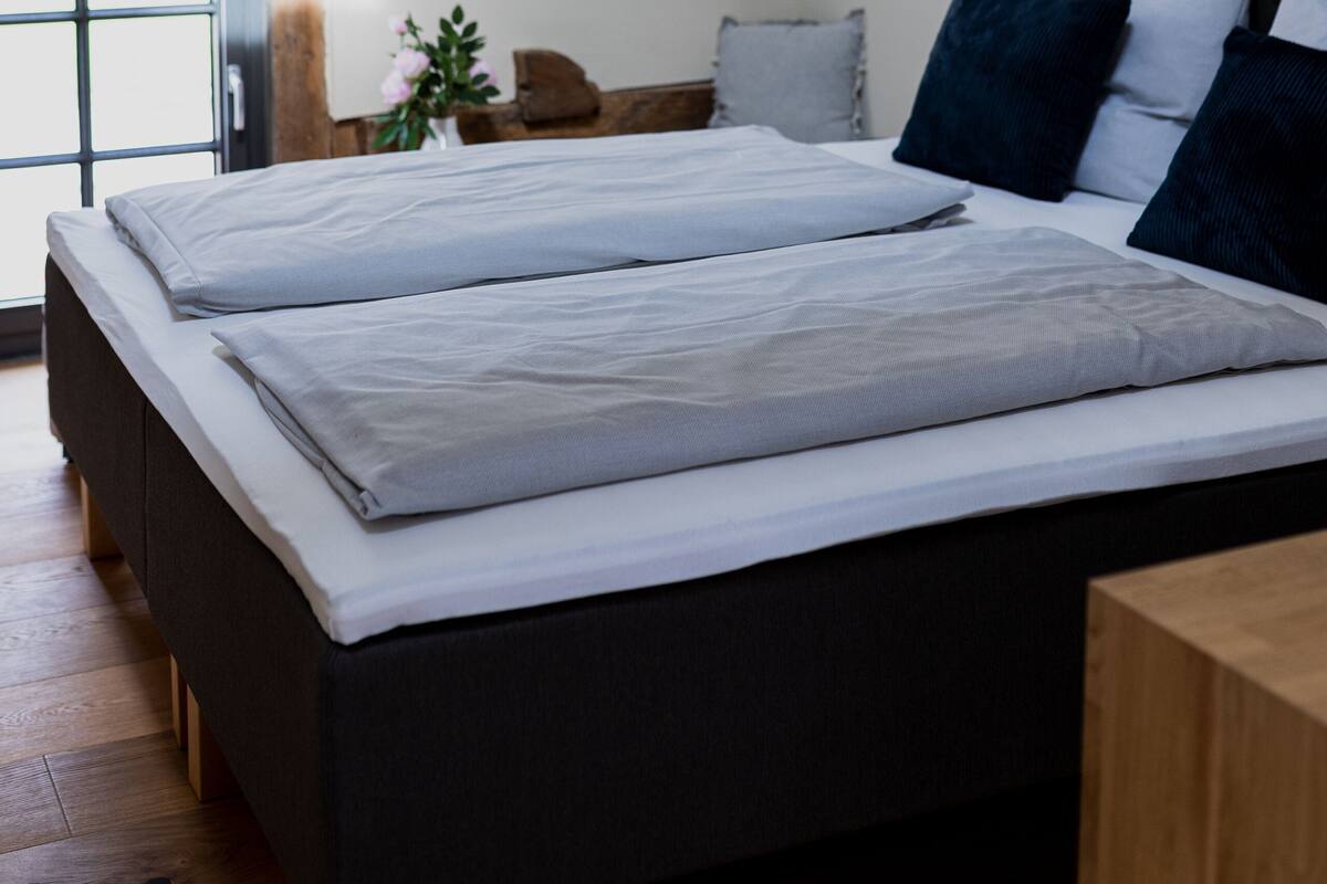 Une chambre à coucher avec un lit, une table de chevet, une lampe et une fenêtre.