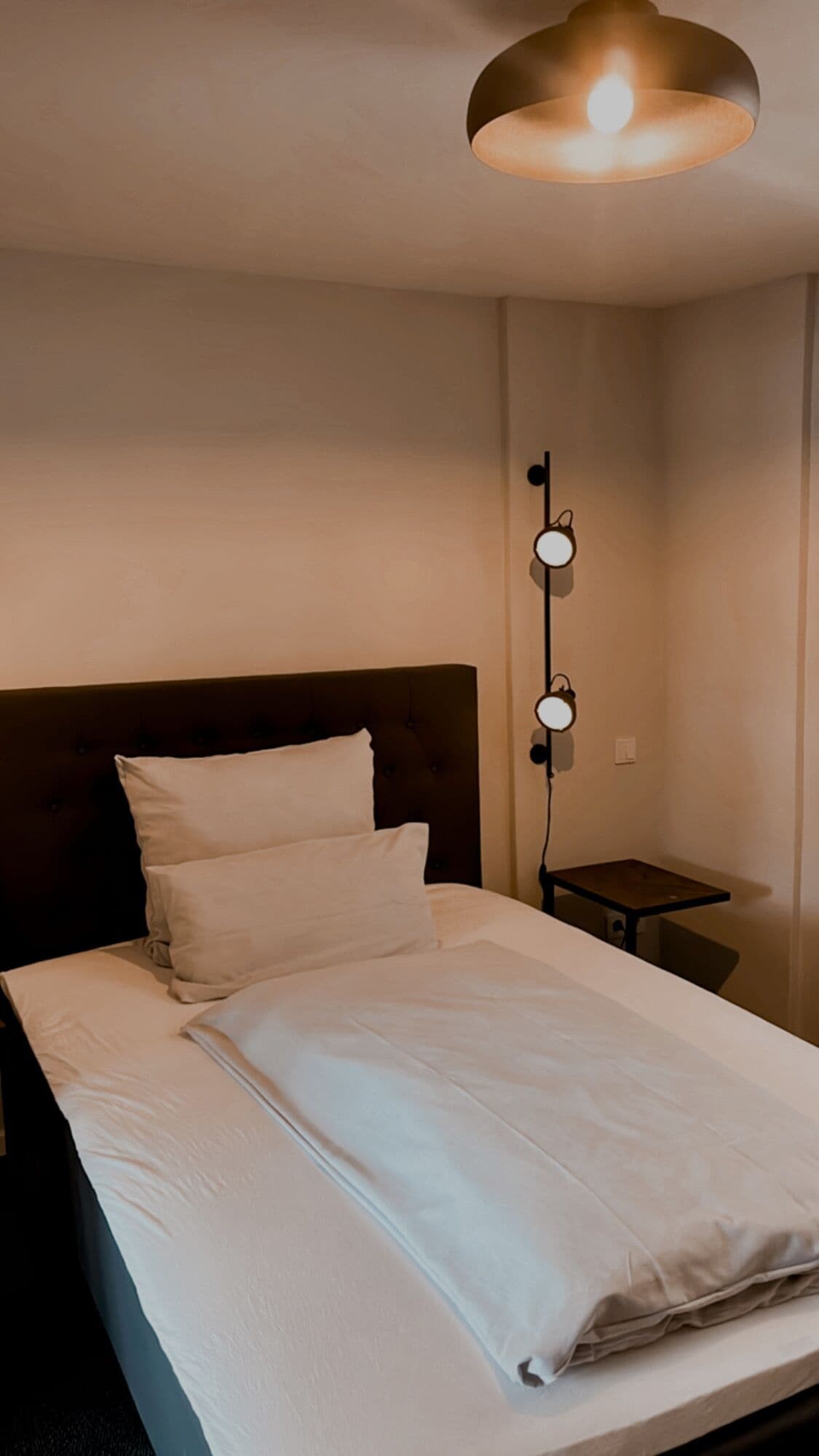 A neatly made bed with white linens in a hotel room.