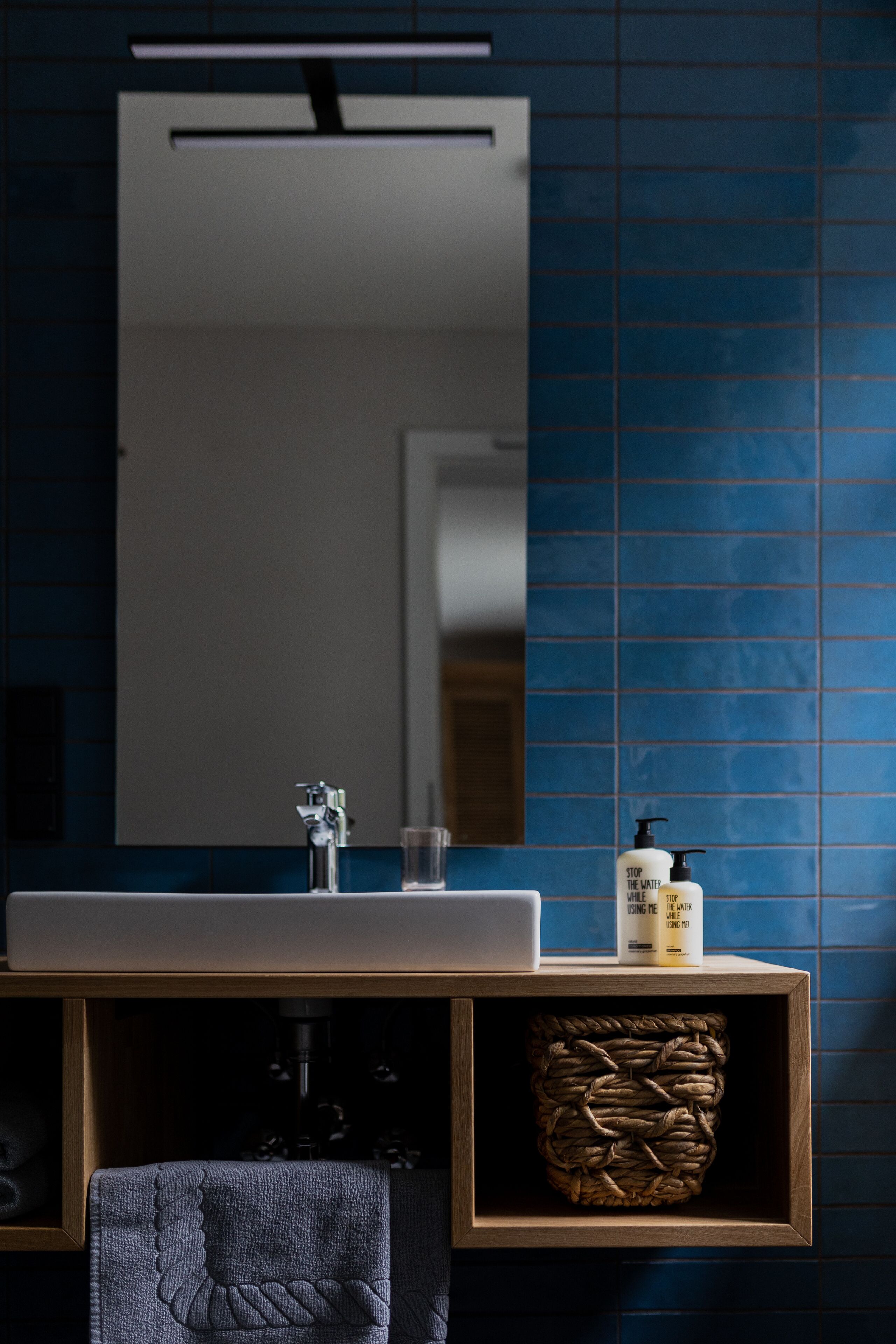 A bathroom with a sink, mirror, and toiletries.