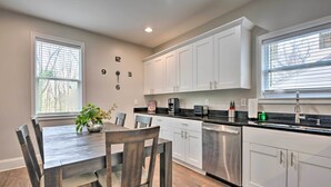 A modern kitchen with white cabinets, a wooden dining table, and a potted plant. - Chic Atlanta Home < 4 Mi to Mercedes-benz Stadium! (Atlanta)