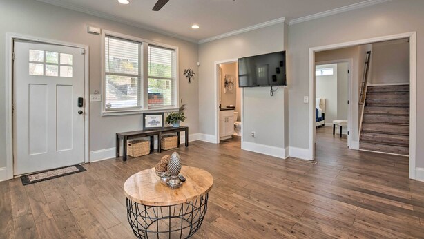 A spacious living room with hardwood flooring, a ceiling fan, a round coffee table, and a flat-screen TV mounted on the wall. - Chic Atlanta Home < 4 Mi to Mercedes-benz Stadium! (Atlanta)