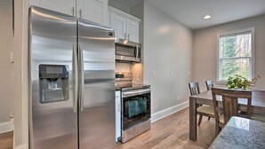 A modern kitchen with stainless steel appliances, a built-in oven, and a dining area with a wooden table and chairs. - Chic Atlanta Home < 4 Mi to Mercedes-benz Stadium! (Atlanta)