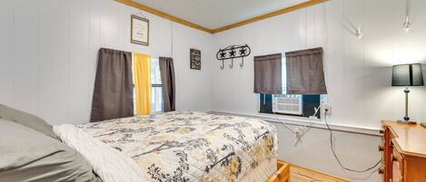 A bedroom with a bed, wooden dresser, and a window with curtains.