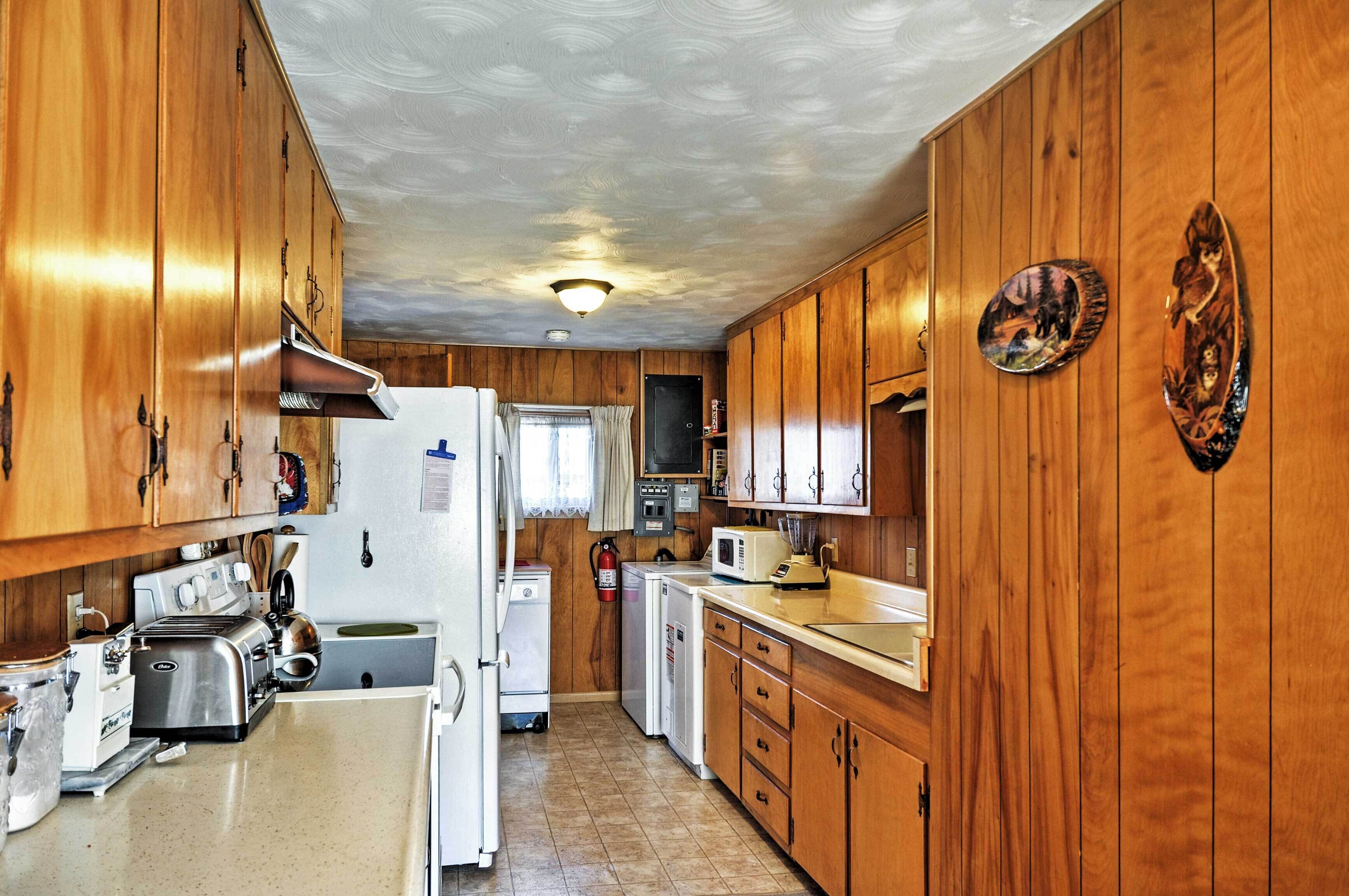 Eine kleine Küche mit Holzausstattung, einem Kühlschrank, einer Mikrowelle und einem Toaster.