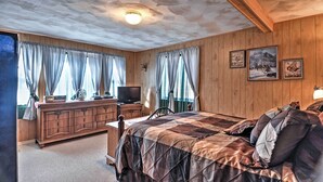 Camera da letto con rivestimento in legno, un letto, una cassettiera e un televisore.