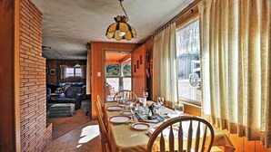Zona pranzo con parete in mattoni, soffitto in legno e tavolo imbandito per quattro persone.