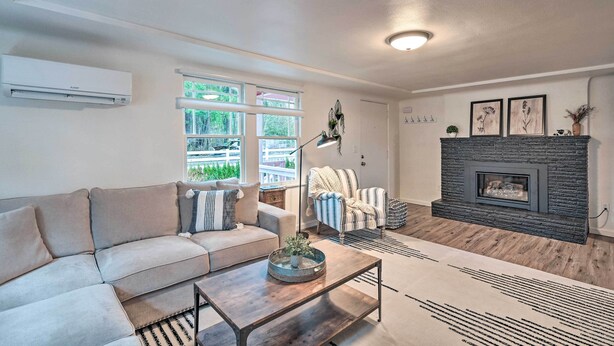 A living room with a sofa, a coffee table, a fireplace, and large windows.