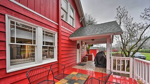 A red house with a porch, a table, and two chairs.