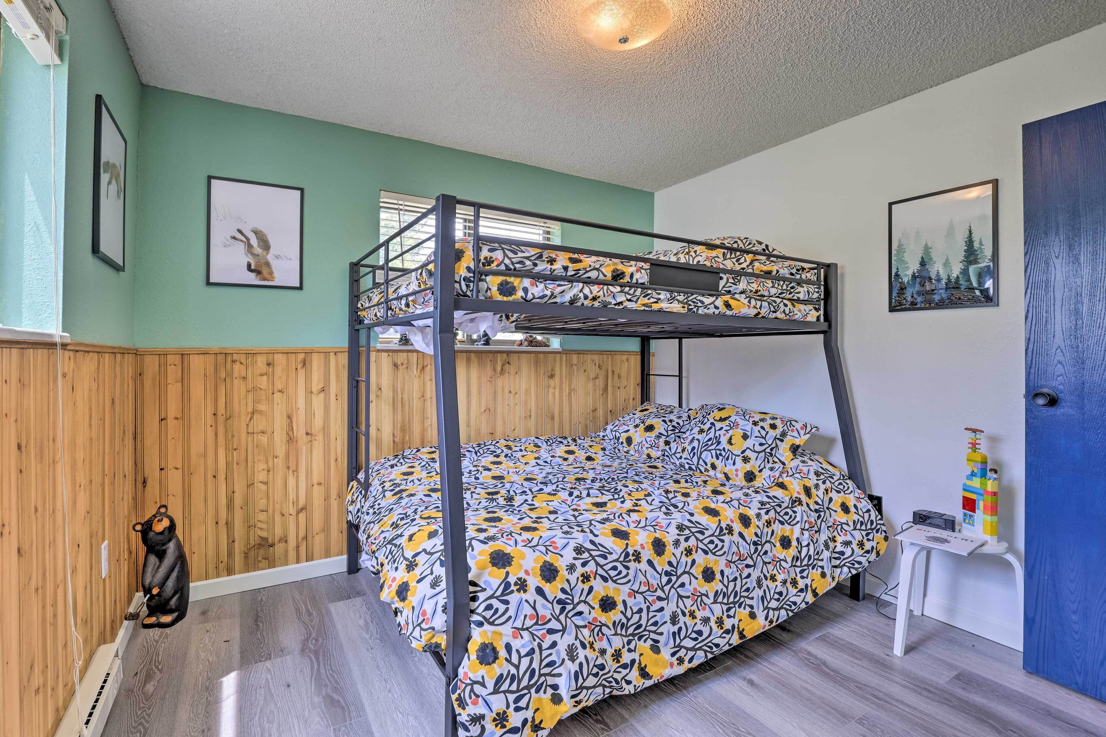 Habitación con literas, colcha estampada con motivos florales, paneles de madera en las paredes y una pequeña mesa con un adorno.