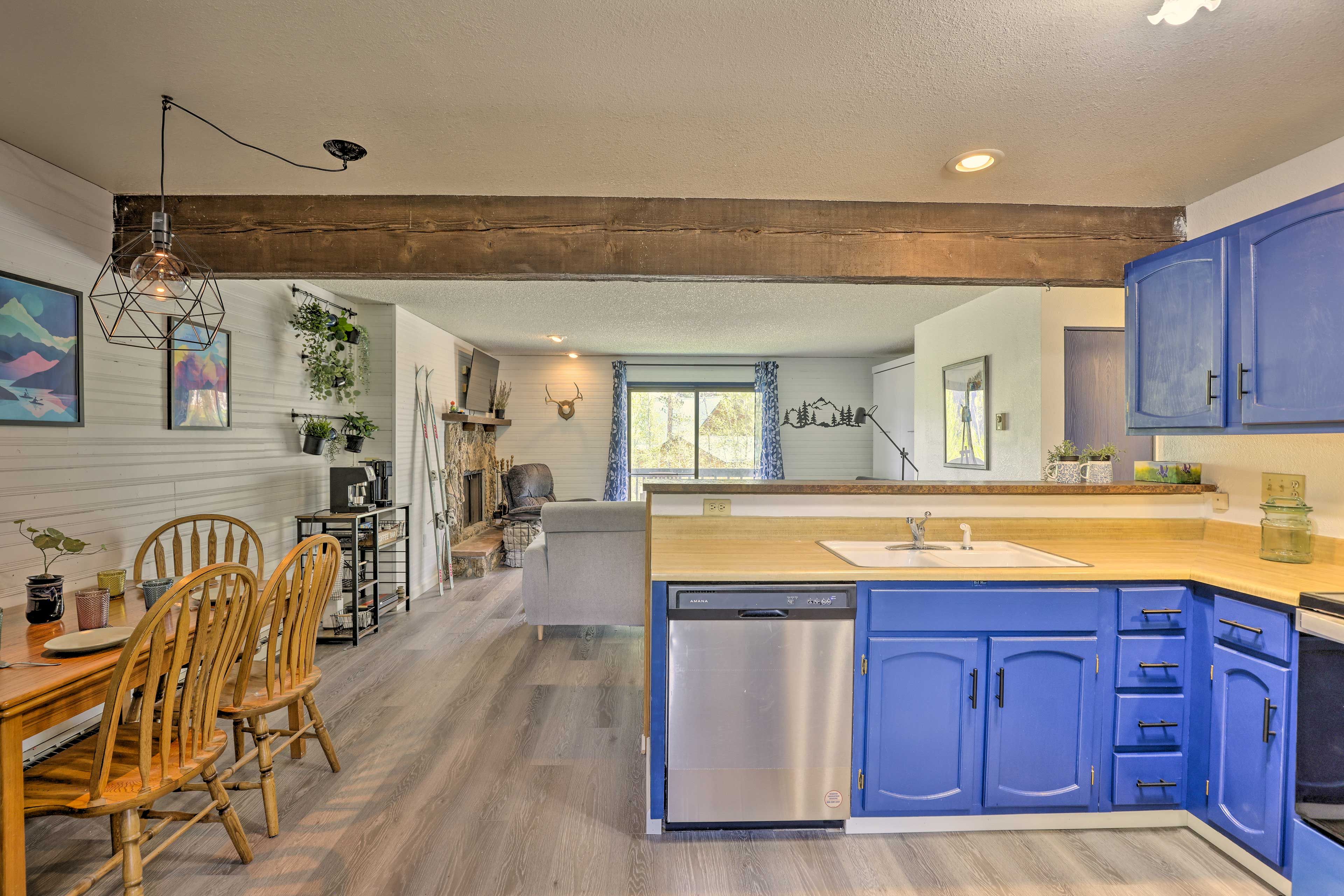 A modern kitchen with blue cabinets, a dishwasher, and wooden chairs.
