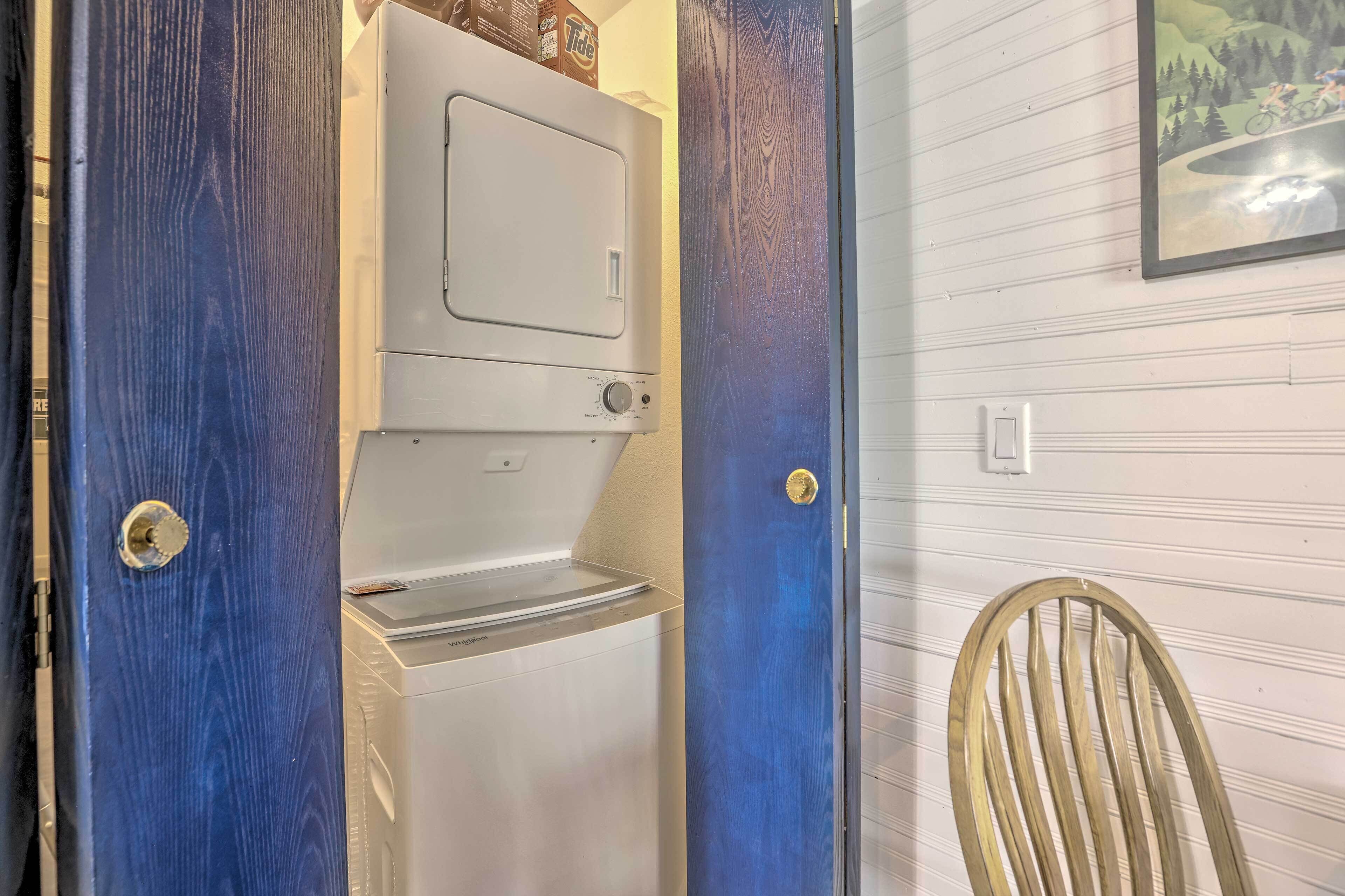 A compact room with a built-in washer and dryer, a wooden chair, and a framed picture on the wall.