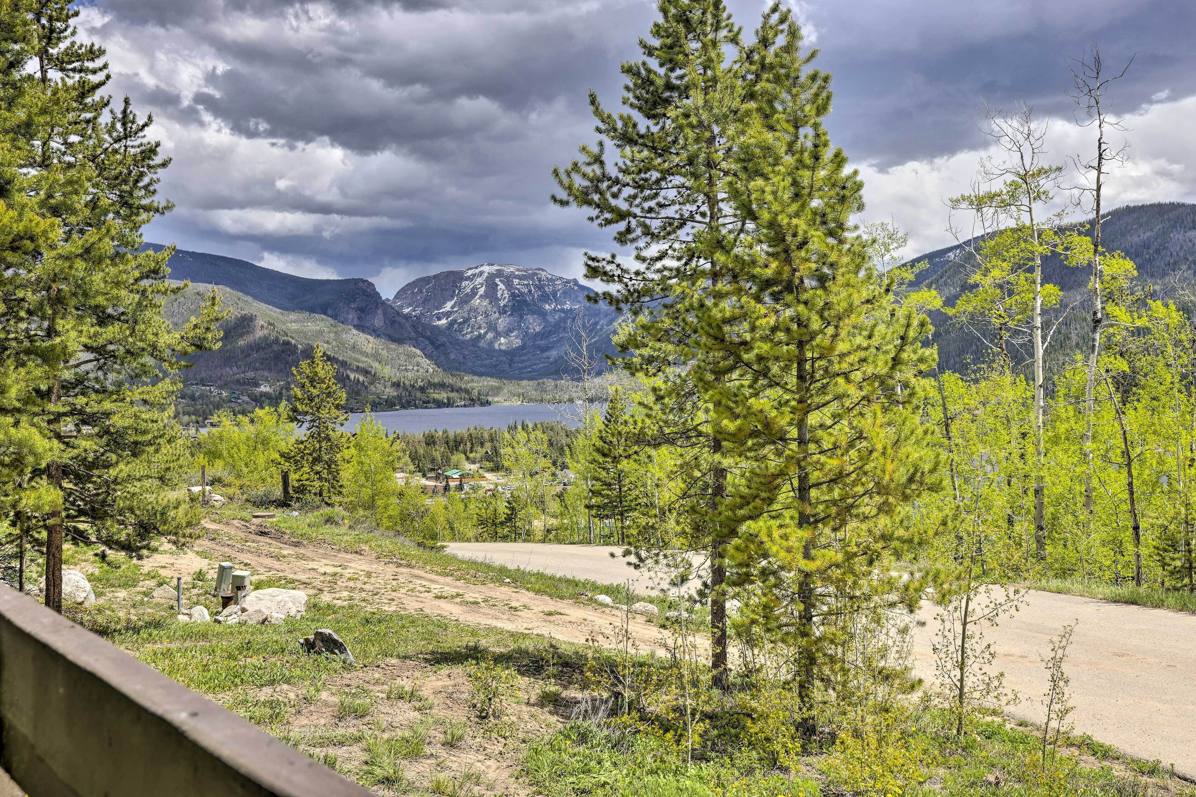 A mountainous landscape with a lake, surrounded by trees and a dirt path.