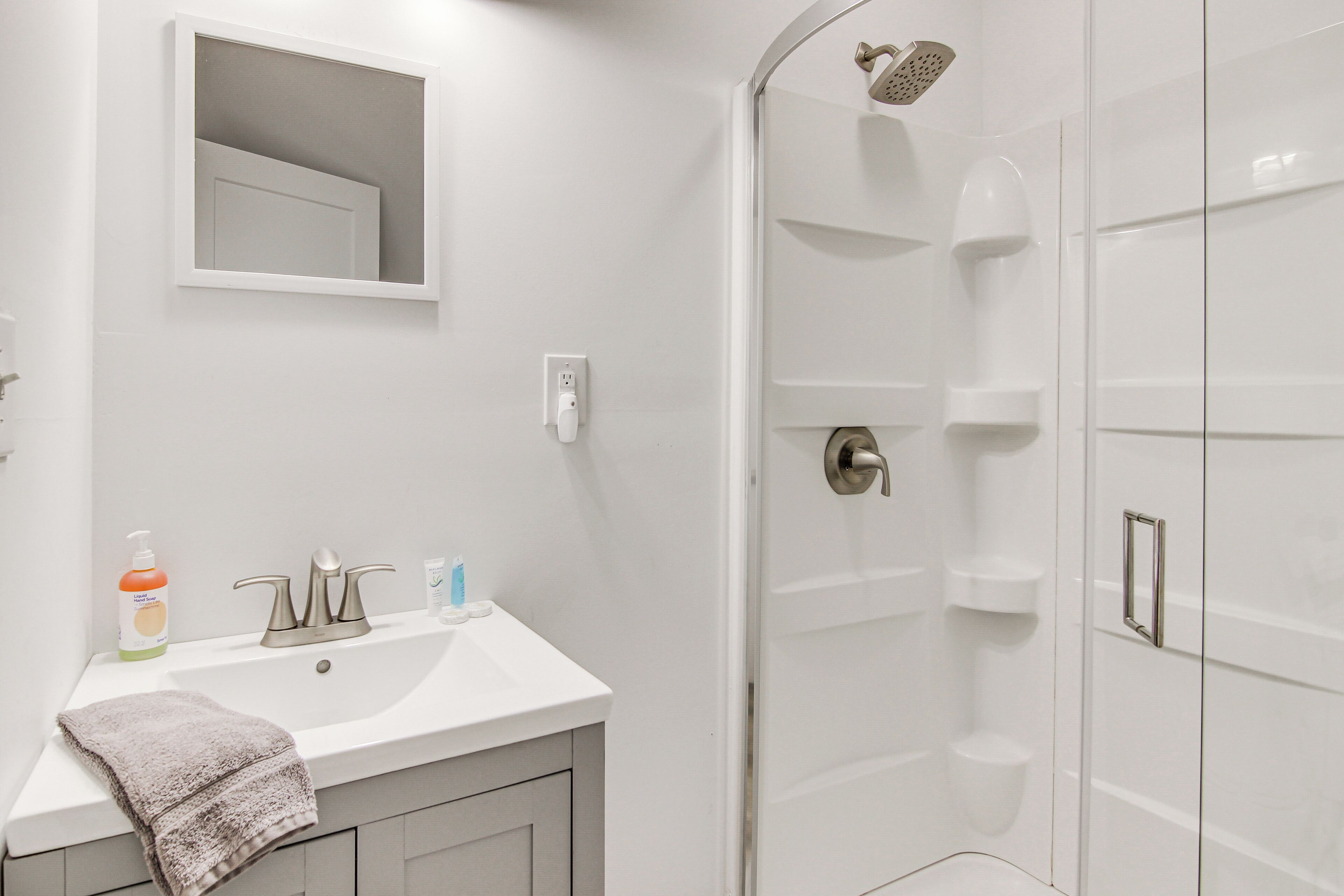 A bathroom with a white sink, a mirror, and a shower enclosure.