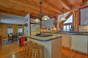 Una cocina acogedora de estilo rústico con vigas de madera, una isla central con taburetes y un refrigerador.