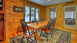 A wooden dining room with a large table and chairs, framed pictures on the wall, and large windows. - Spacious Gilford Retreat w/ Deck: 2 Mi to Skiing! (Gilford)
