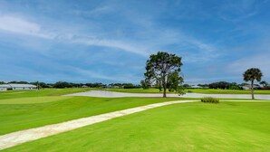A well-maintained golf course with a clear path, a large tree, and a body of water. - 1 Mi to Golf: Sebring Condo w/ Pool Access! (Sebring)