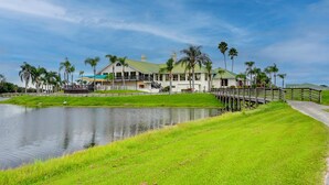 A waterfront property with a large house, a dock, and a grassy area with palm trees. - 1 Mi to Golf: Sebring Condo w/ Pool Access! (Sebring)