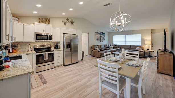 A modern kitchen with white cabinets, stainless steel appliances, and a dining area with a wooden table and chairs. - 1 Mi to Golf: Sebring Condo w/ Pool Access! (Sebring)