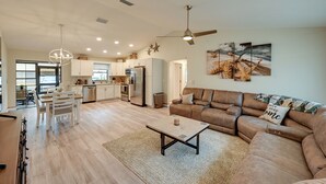A spacious living room with a brown leather sofa, a dining area with a white table and chairs, and a kitchen with white cabinets and stainless steel appliances. - 1 Mi to Golf: Sebring Condo w/ Pool Access! (Sebring)